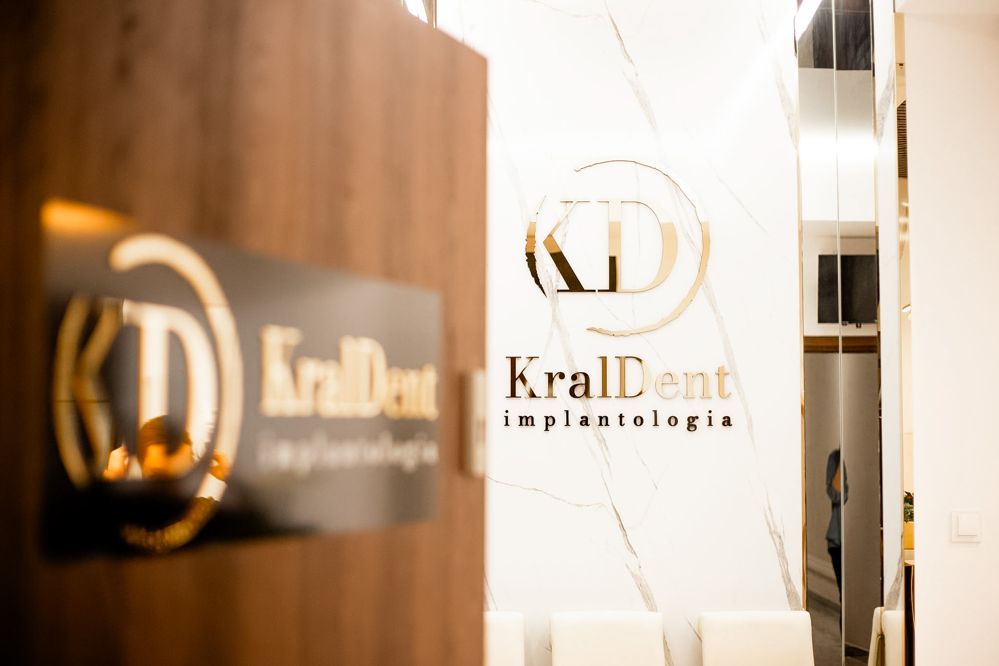 Eleganckie wnętrze gabinetu stomatologicznego KralDent Implantologia w Białymstoku z marmurowym wykończeniem i złotym logo kliniki